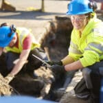 A construction worker inspecting an underground utility line.